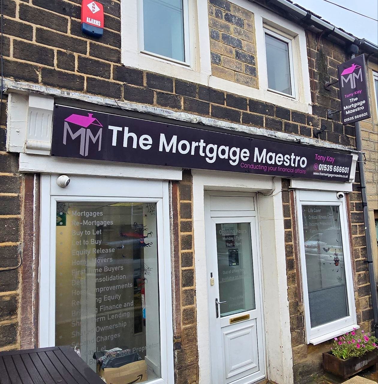 The Mortgage Maestro office on Cross Roads in Keighley: a stone-fronted terrace shopfront with a black fascia sign, white door and two windows listing the services offered